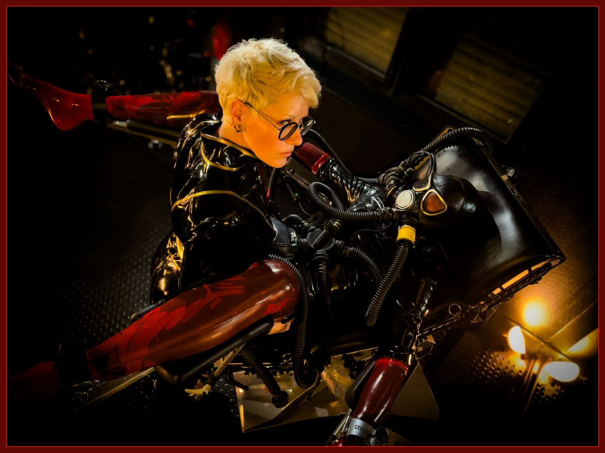 Heavy Rubber Breathplay, Proband liegt auf dem Boomer und Herrin Sonja schaut in die Kamera